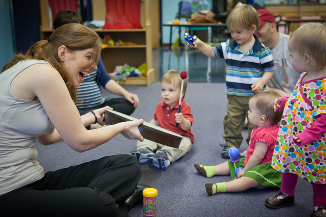 Sprouting Melodies founder and provider, Meredith, shares a frame drum with several young children.