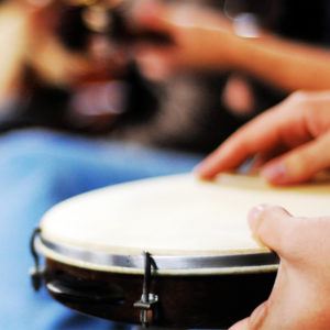 A person holds and plays a hand drum.