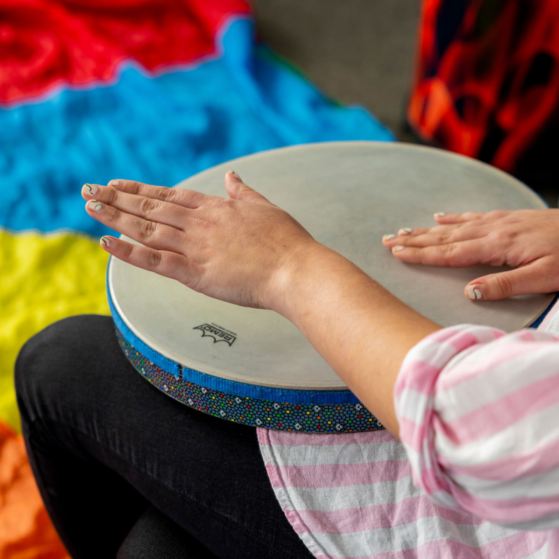 A music therapy intern participates in a drumming experience.