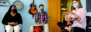 Music therapists sitting with musical instruments and listening to their colleague.